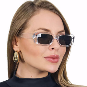 Óculos de sol feminino retrô com armação transparente em acetato italiano e hastes em metal anticorrosivo. Lentes escuras UV400 para proteção total, conforto e estilo sofisticado.