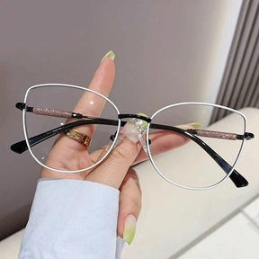 Óculos Anti Luz Azul Feminino com armação olho de gato em liga metálica leve e resistente. Lentes de policarbonato com bloqueio de luz azul para proteger seus olhos e reduzir fadiga ocular. Estilo moderno para qualquer ocasião.