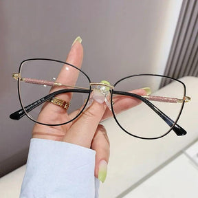 Óculos Anti Luz Azul Feminino com armação olho de gato em liga metálica leve e resistente. Lentes de policarbonato com bloqueio de luz azul para proteger seus olhos e reduzir fadiga ocular. Estilo moderno para qualquer ocasião.